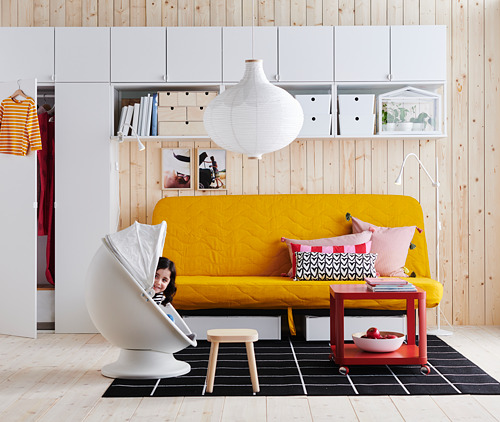Sofá amarillo, almohadas de colores, habitación moderna, lámpara blanca, silla única, camisa a rayas, alfombra negra.