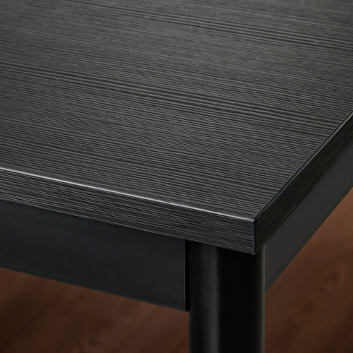 Primer plano de una mesa elegante de color oscuro con tapa lisa y brillante y bordes metálicos resistentes.
