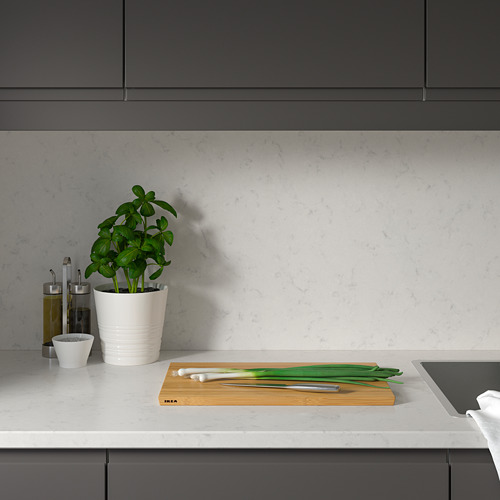 Cocina moderna con mesada de cuarzo blanco, planta, cebolla, cuchillo; Armarios grises.