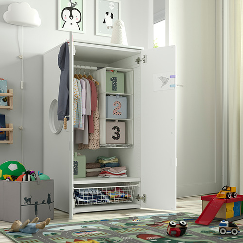 Armario infantil con puerta abierta, que muestra ropa, cajas y juguetes, que demuestra el almacenamiento accesible.