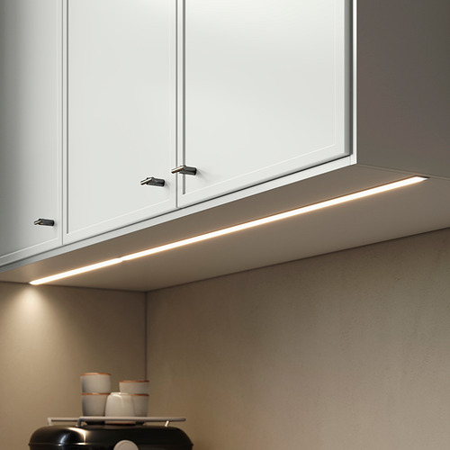 Tira de iluminación bajo los armarios, gris elegante, diseño moderno, se inserta debajo de los armarios blancos de la cocina.