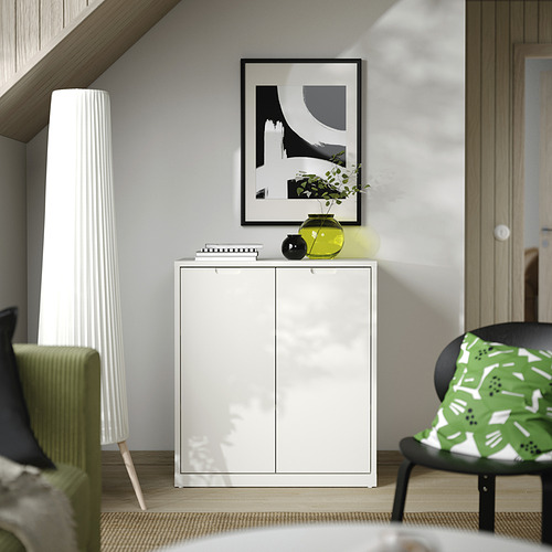 Habitación minimalista con mueble TONSTAD blanco, jarrón de cal, arte abstracto y silla con estampado verde.