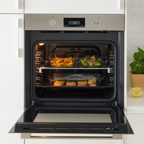 Un horno abierto de acero inoxidable con alimentos en rejillas, que muestra la hora digital.