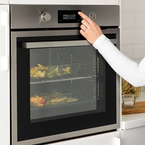 Persona que utiliza un moderno horno de convección controlado por contacto. O la persona activa el horno de convección con controles táctiles.