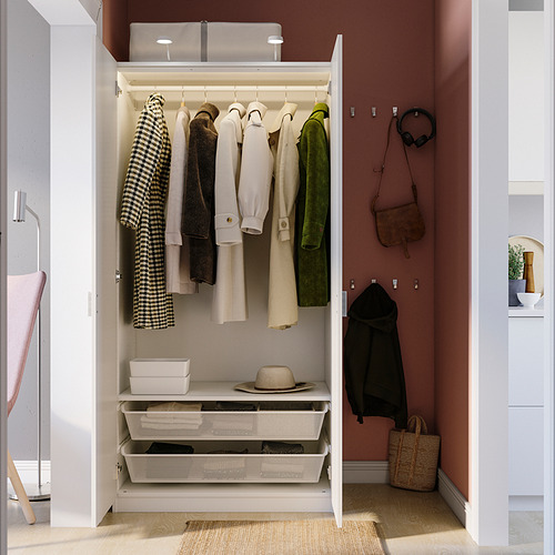 Armario cerrado con abrigos colgantes, sombrero y cubos de almacenamiento. Los ganchos de pared sujetan la bolsa y los auriculares. Forma parte de una serie PAX.