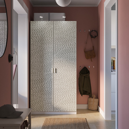 Dormitorio moderno con armario PAX estampado, paredes rosas, alfombra tejida y artículos personales.