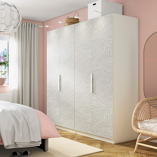 Elegante dormitorio con armario PAX de puntos blancos, puertas dobles y cestas de malla. Pieza central entre cama, silla de mimbre y espejo grande.