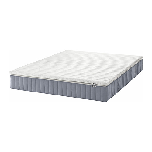 Un colchón de muelles ensacados VALEVÅG blanco y gris. Es rectangular y tiene una superficie superior texturizada y paneles laterales grises con pliegues verticales.
