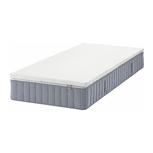Un colchón de muelles ensacados VALEVÅG de IKEA blanco y gris. Tiene un diseño lateral gris acolchado con una etiqueta de marca visible.