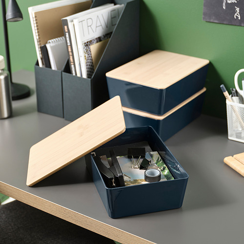 Tres cajas azules de KUGGIS hechas de plástico reciclado y bambú, guardando y apilando cuidadosamente los suministros de oficina.