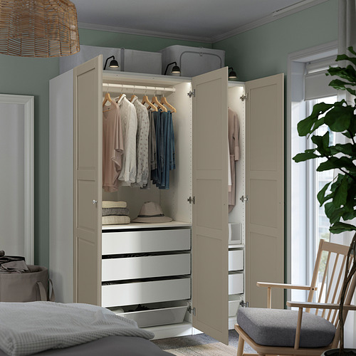 Dormitorio moderno con armario PAX beige abierto que revela ropa, cajones y accesorios en estantes. Las luces tenues resaltan el espacio organizado.