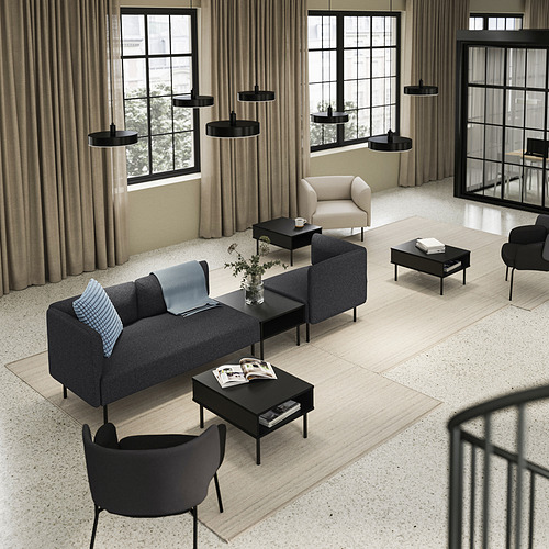 Moderno salón con sofá gris LILLEHEM, mesas de centro negras, lámparas colgantes y grandes ventanales con cortinas beige.
