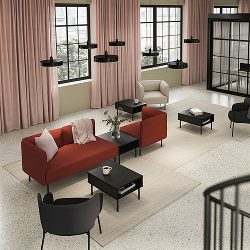 Sala de estar moderna con sofá LILLEHEM rojo, mesas de centro negras y lámparas colgantes negras.