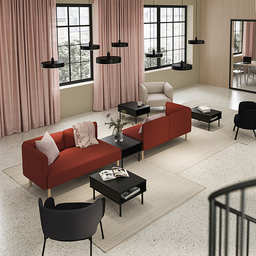 Sala de estar moderna con sofá LILLEHEM rojo, mesas de centro negras, sillones y cortinas rosas.