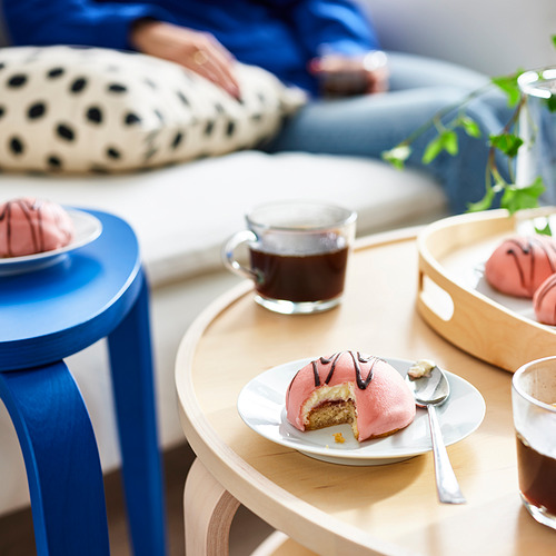 Una configuración acogedora con pasteles de crema rosa, café y asientos cómodos para socializar.