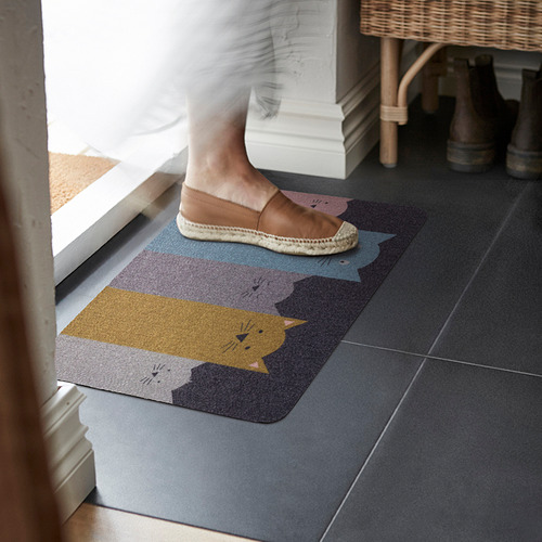 La persona pisa la alfombra TURISTVÄG con temática de gatos en la entrada.