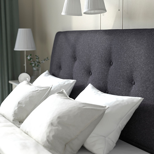 Acogedora cama con cabecero gris, almohadas blancas y lámparas. Cajones de cierre suave debajo de la cama.