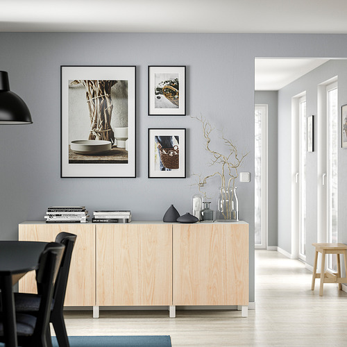 Sala de estar moderna con gabinete de madera clara, varios jarrones, fotos enmarcadas y silla de comedor negra.