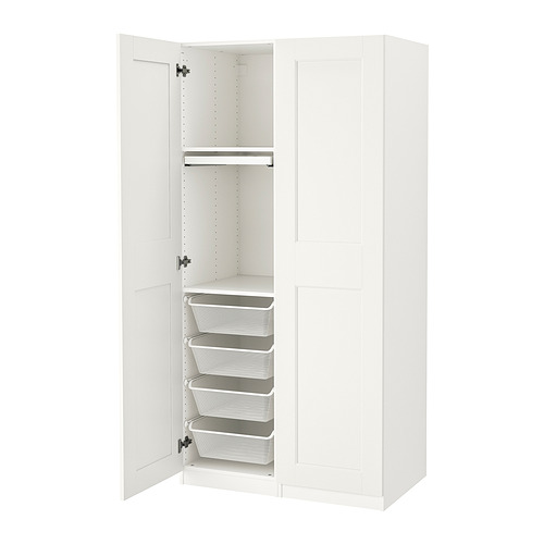 Un armario blanco de IKEA PAX con una puerta abierta, cajones reveladores y cestas de malla en el interior.