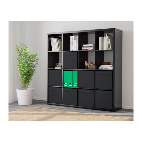 Estantería KALLAX negra con mezcla de almacenamiento abierto y cerrado, con capacidad para libros y artículos de decoración, colocada contra una pared.