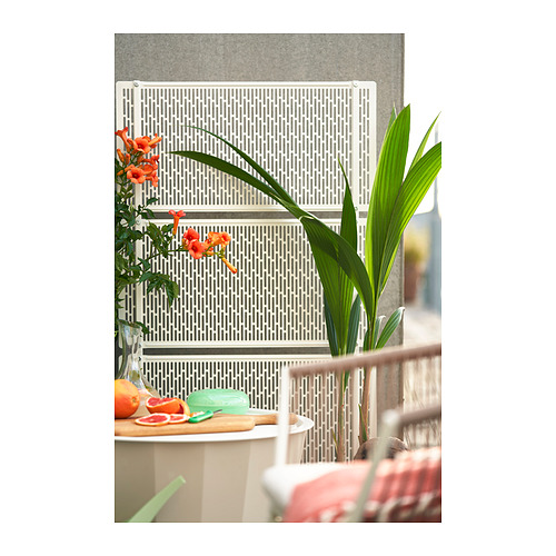 Pantalla de privacidad blanca con celosía, acero y plástico, ideal para jardín o terraza, con flores a la izquierda, planta a la derecha.