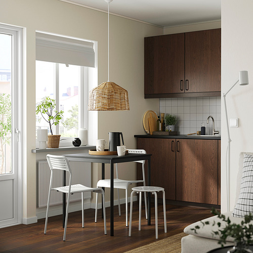 Cocina moderna: gabinetes de madera oscura, azulejos blancos, piso de madera. Juego de comedor junto a la ventana, lámpara de mimbre, plantas y encimera de cocina con fregadero.