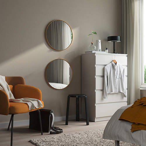 Dormitorio moderno con espejos dorados, silla naranja y manta de cama amarilla.