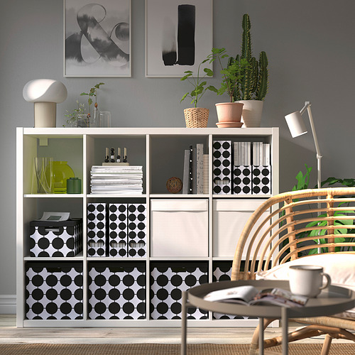 Área de trabajo de estilo moderno con revistero TJENA junto a plantas verdes, sosteniendo papeles y debajo arte abstracto.