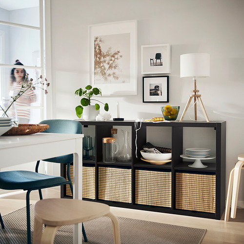 Comedor moderno con estanterías KALLAX, cestas, decoración, plantas, sillas azules, lámpara blanca.