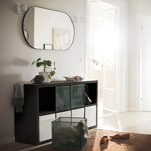 Unidad de almacenamiento KALLAX en blanco y negro con contenedores de malla, planta, espejo; Elegante y práctica configuración de la nave.