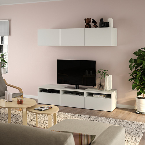 Sala de estar moderna con banco de televisión BESTÅ, TV de pantalla plana, pared de color rosa claro, plantas y decoración minimalista.