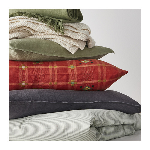 Pila de almohadas de colores: rojas, verdes, grises y blancas; El rojo tiene un patrón de cinturón de monje a cuadros.