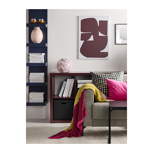 Sala de estar moderna con estantería de madera oscura, sofá gris, manta colorida y arte abstracto.