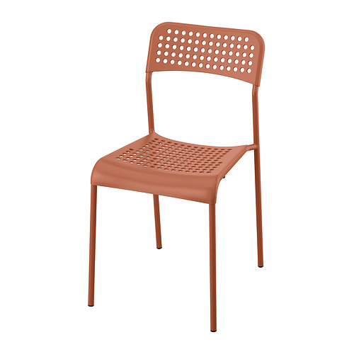 Representa una silla de plástico sandberg naranja con asiento y respaldo perforados, sostenida por cuatro patas metálicas.