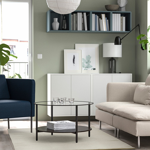 Sala de estar verde con mesa TIDTABELL, jarrones, alfombra beige, sofá blanco, silla azul marino y libros.