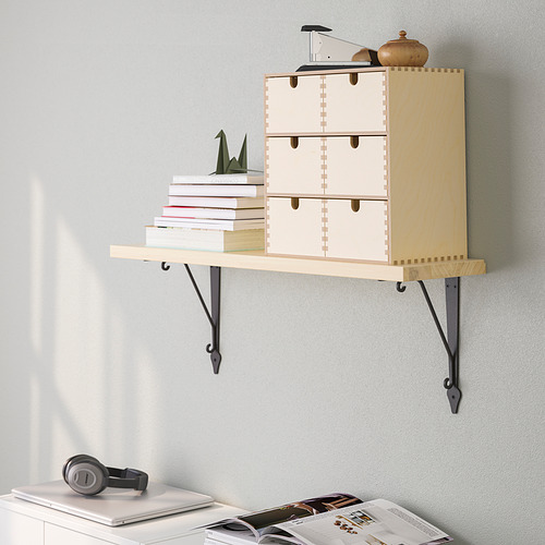 El estante de madera montado en la pared sostiene libros y artículos decorativos, liberando espacio en el piso.
