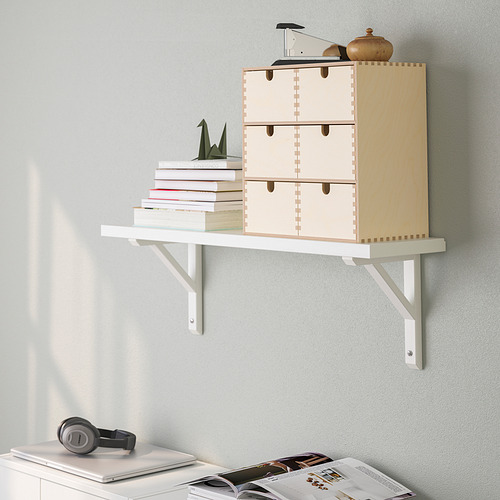 Una estantería de pared con cajones y soportes de madera. Almacena libros y contiene varios artículos.