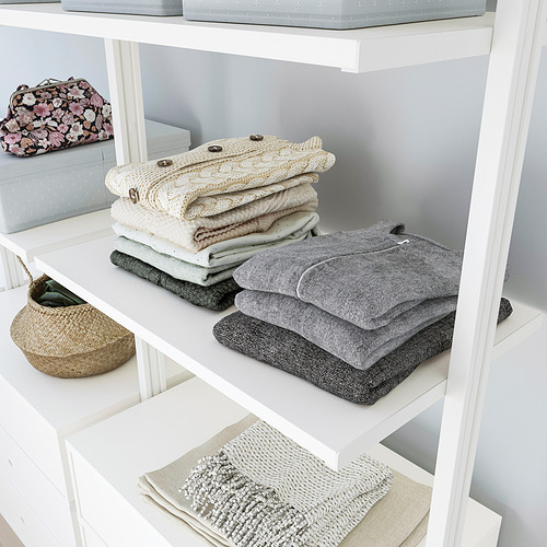 La estantería ELVARLI exhibe ropa y mantas cuidadosamente dobladas, utilizando el espacio de manera eficiente con almacenamiento personalizable.