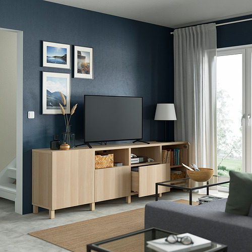 Sala de estar moderna con televisor grande sobre soporte de madera, con estantes ajustables, cajones y administración de cables.