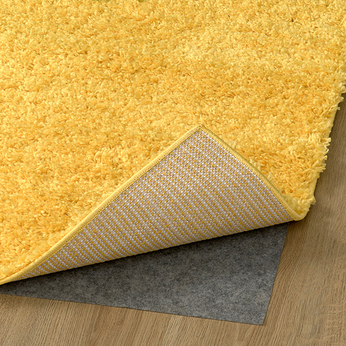 Alfombra peluda de color amarillo brillante con respaldo texturizado, parte de una serie de alfombras diseñadas para la comodidad y la absorción del sonido.