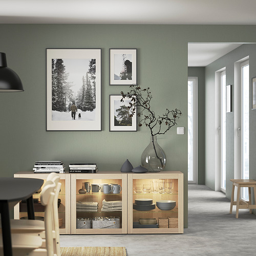 Comedor moderno con aparador de madera clara BESTÅ, donde se exhiben platos y decoración.