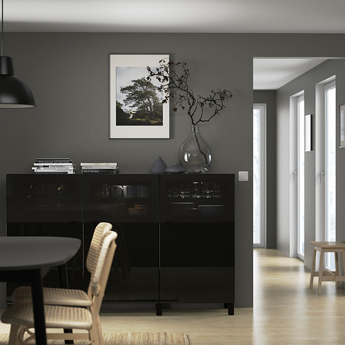 Comedor moderno con aparador GLASSVIK, vidrio ahumado, manijas elegantes y una decoración minimalista con un estampado de la naturaleza y ramas en un jarrón.