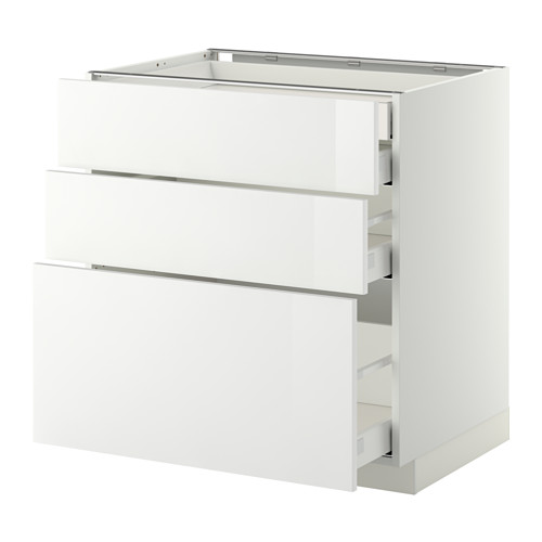 Conjunto de armarios de cocina blancos brillantes con tres cajones y un cajón grande parcialmente extraído. Diseño moderno y elegante.