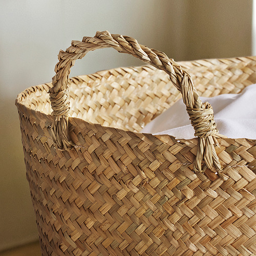 Cesta tejida a mano con asas robustas y retorcidas, que muestra un intrincado tejido de juncos, perfecta para el almacenamiento en casa.