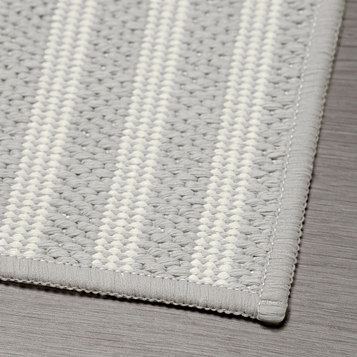 Alfombrilla de cocina tejida gris texturizada sobre suelo de madera, que muestra artesanía y diseño de calidad.