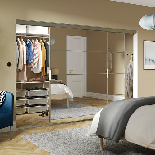 Dormitorio con gran armario SKYTTA con espejos, cama reflectante y silla, complementado con silla azul.
