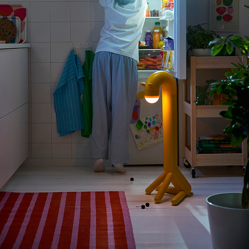 Niño en la nevera, lámpara de jirafa cercana.