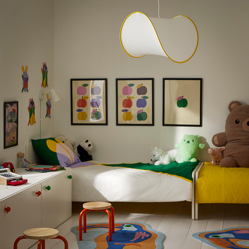 Dormitorio infantil con cama blanca, alfombras de colores, peluches y una moderna lámpara de techo con un diseño lúdico y desplegable que proporciona una luz suave.