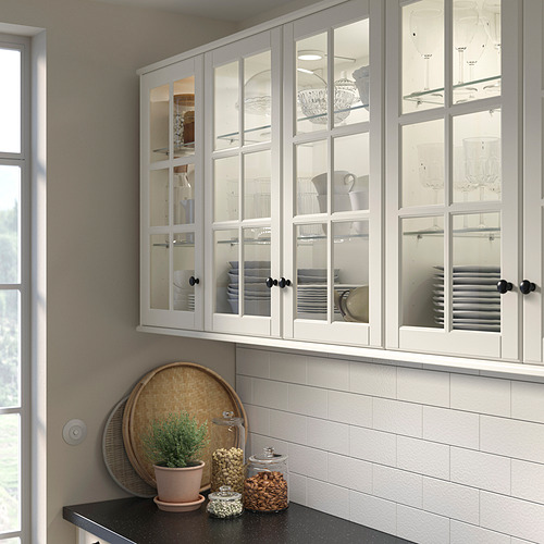 Cocina moderna con gabinetes blancos llenos de cristalería, platos y tazones. Diseño clásico. Mostrador negro con frascos y una planta.