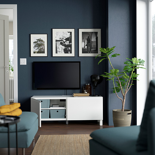 Sala de estar moderna con soporte de TV BESTÅ, estantes ajustables, puertas de cierre suave, TV de pantalla plana, asientos turquesa y planta.